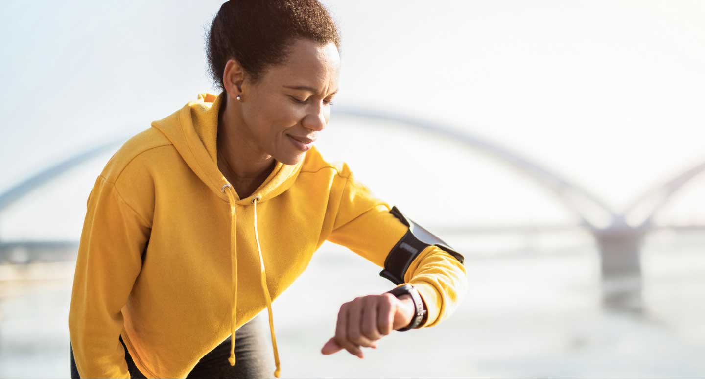 Woman looks at fitness device on wrist