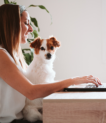 Woman at laptop with dog in lap
